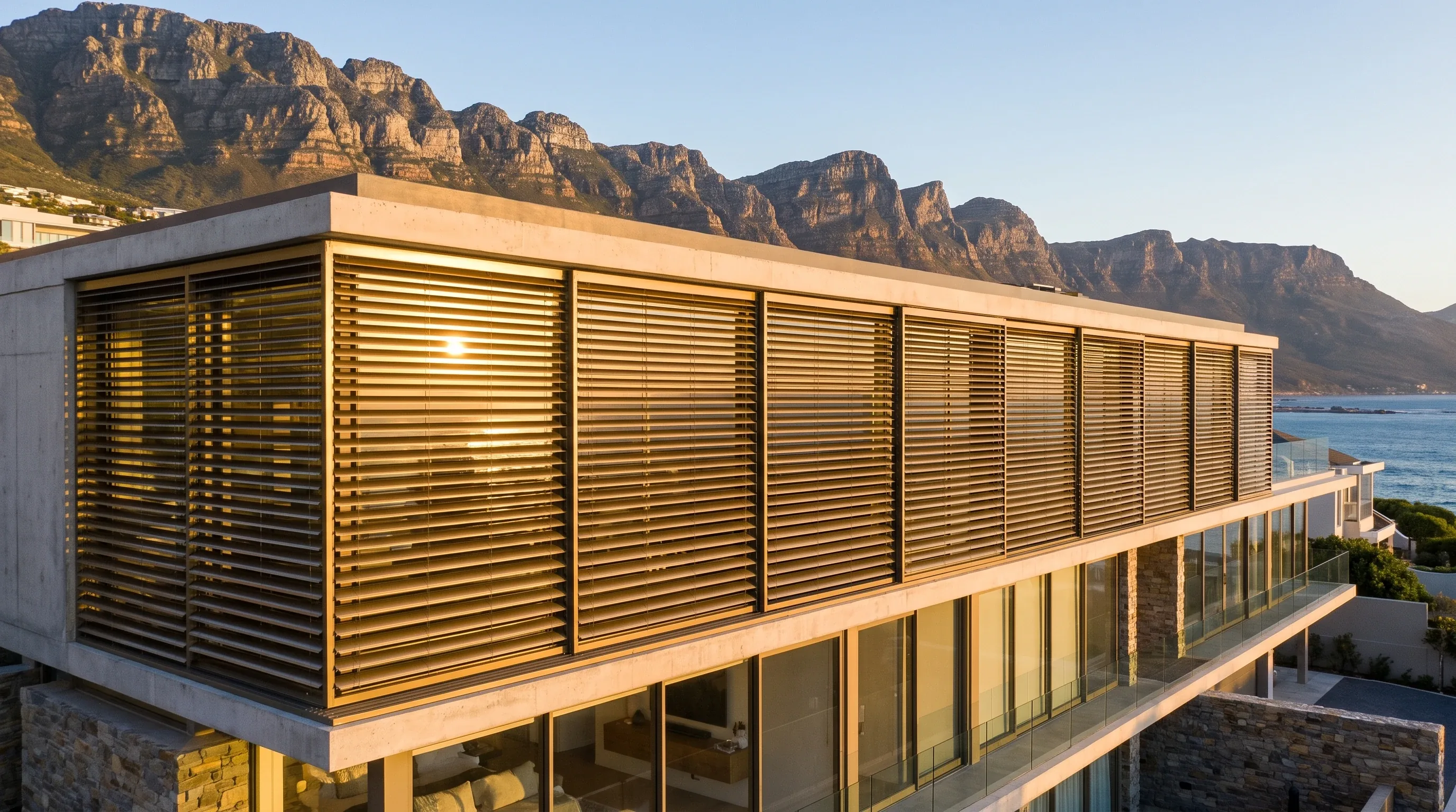 Aluminium external venetian blinds catching golden-hour light across a Camps Bay hillside villa facade